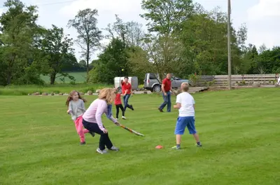 a group of children playing baseball in a field at Curlew Cottage in Church Stretton