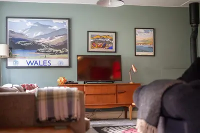 a living room with a flat screen tv on a dresser at Ty'r Adar at Graig Wen in Arthog