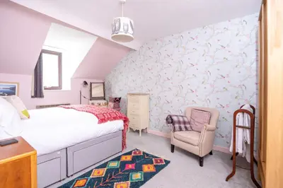 a bedroom with a bed and a chair at Ty'r Adar at Graig Wen in Arthog