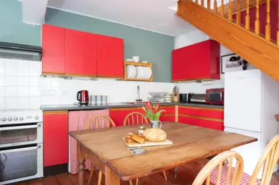 a kitchen with red cabinets and a wooden table at Ty'r Adar at Graig Wen in Arthog