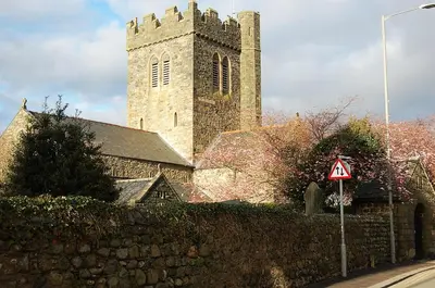 a church with a tall tower with a stone wall at Ty Del - Beautiful Home in Tywyn in Tywyn
