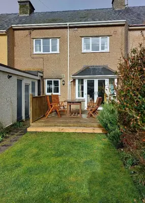 a wooden deck with a table and chairs in front of a house at Garreg Wen - White Stone, family holiday home in Barmouth