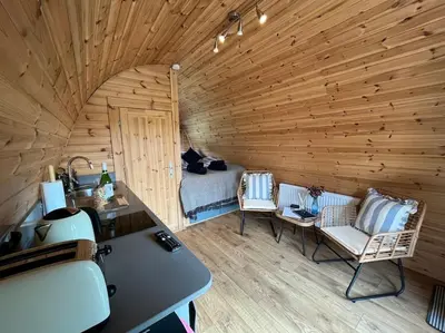 a room with two chairs and a bed in a wooden room at The Pod Patch - Trelerney Pod in Bishops Castle