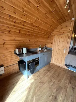a kitchen in a wooden cabin with a counter top at The Pod Patch - Trelerney Pod in Bishops Castle