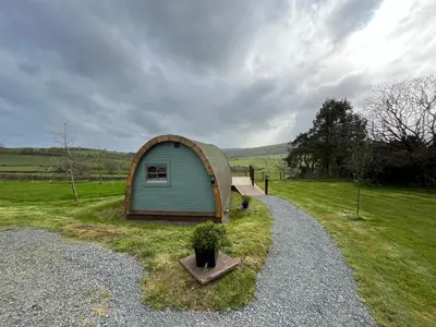 a small shed sitting on top of a grass field at The Pod Patch - Trelerney Pod in Bishops Castle