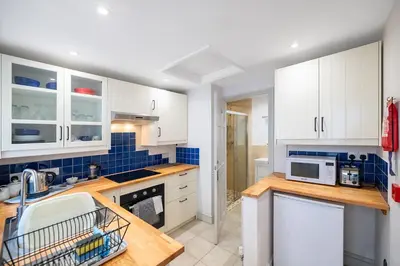 a kitchen with white cabinets and blue tiles at Ground Floor Sea View Apartment in Aberdyfi