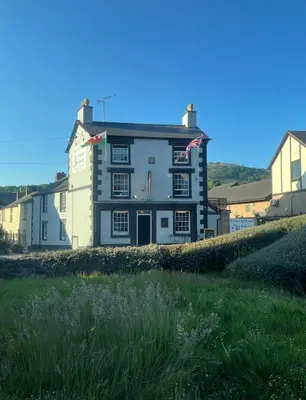 a large white building on the side of a field at Prince of wales pub and accommodation in Llangollen