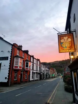 an empty street with a sign hanging from a building at Prince of wales pub and accommodation in Llangollen