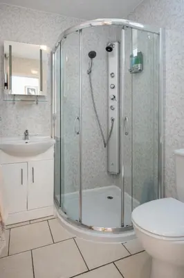 a bathroom with a shower with a toilet and a sink at Estuary Lodge Motel in Talsarnau