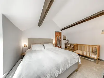 a bedroom with a white bed and a crib at Dee Bank Cottage in Llangollen