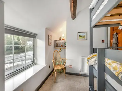 a small bedroom with a window and a chair at Dee Bank Cottage in Llangollen