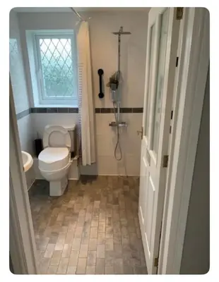 a bathroom with a toilet and a shower and a window at The Little House, Oswestry in Oswestry