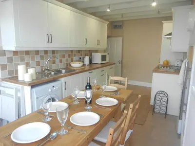 a kitchen with a wooden table with plates and wine glasses at 3 Prospect Place New Quay in New Quay