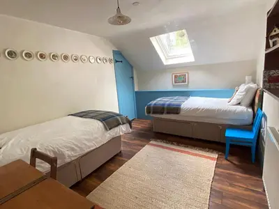 a bedroom with two beds and a table and a window at Creatively converted barn in accessible rural spot in Llanwrda