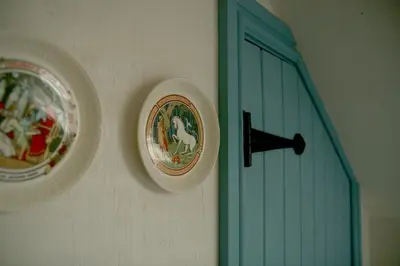 two plates on a wall next to a blue door at Creatively converted barn in accessible rural spot in Llanwrda