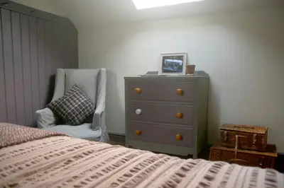 a bedroom with a dresser and a bed and a chair at Creatively converted barn in accessible rural spot in Llanwrda