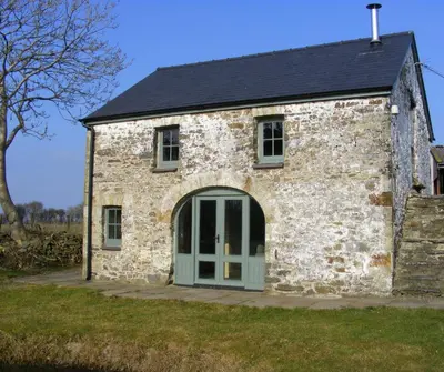an old stone barn with a green door at The Coach House New Quay in Cross Inn