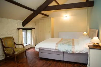 a bedroom with a bed and a chair in it at The Coach House New Quay in Cross Inn