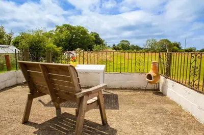 a wooden bench sitting in front of a fence at The Coach House New Quay in Cross Inn