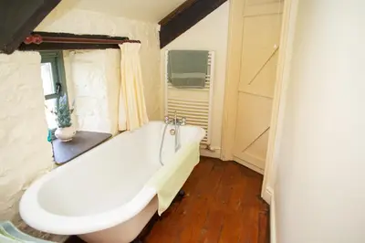 a bath tub in a bathroom with a window at The Coach House New Quay in Cross Inn