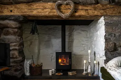 a fireplace on a table in a stone room at Pen-Y-Bryn Cottage in Blaenau-Ffestiniog