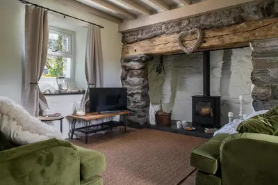 a living room with a stone fireplace and a television at Pen-Y-Bryn Cottage in Blaenau-Ffestiniog