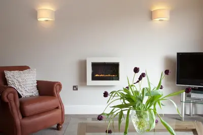 a living room with a chair and a fireplace at Hay Retreats in Hay-on-Wye