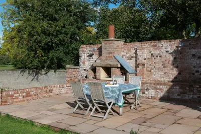 a table and chairs with a brick oven at The Hop Kiln in Leominster