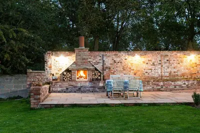 a brick wall with a table and chairs and a fireplace at The Hop Kiln in Leominster