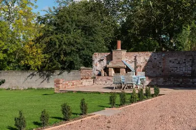 a brick building with two chairs and a fireplace at The Hop Kiln in Leominster