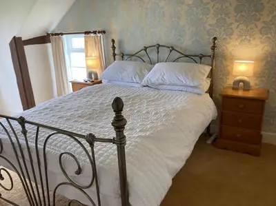 a bedroom with a large bed with white sheets and pillows at Bryntirion Farmhouse Rooms (with bathroom) in Llanfair Caereinion