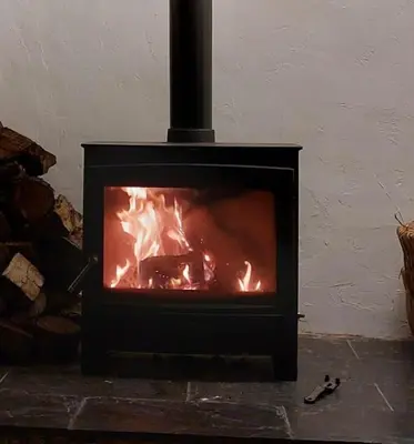 a fireplace with a fire inside of it at Bryntirion Farmhouse Rooms (with bathroom) in Llanfair Caereinion