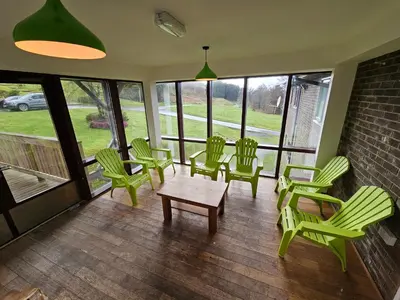 a room with green chairs and a table and a group of windows at Rural Group Lodging 19 rooms 83 beds Games room in Elerch