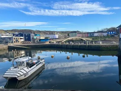 a boat is docked in the water near a city at Nant Meigan, Georgian Townhouse in centre of Aberaeron, dog friendly in Aberaeron