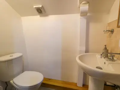 a white bathroom with a toilet and a sink at Graig Las The Stables in Oswestry
