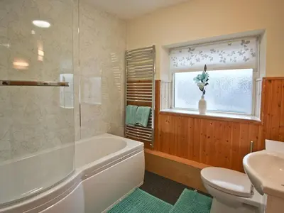 a bathroom with a tub and a toilet and a window at Cob Cottage in Tregaron