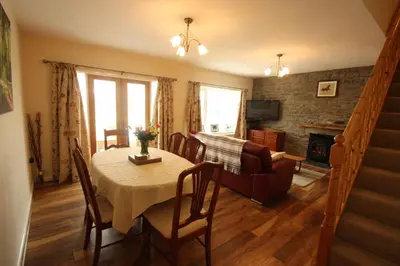 a dining room and living room with a table and a couch at Cob Cottage in Tregaron