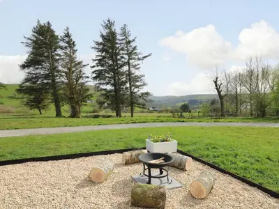 a fire pit on a gravel patio with a field at Willow in Llanidloes