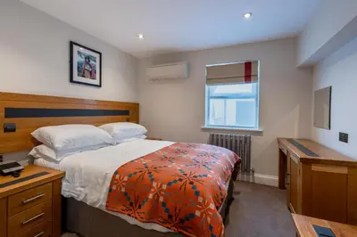 a bedroom with a bed and a desk and a window at Gwesty Cymru in Aberystwyth