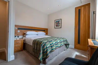 a bedroom with a bed with a wooden headboard and a desk at Gwesty Cymru in Aberystwyth