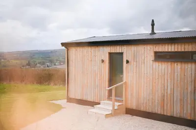 a small wooden building with a door and stairs at Cae Bedw in Newtown