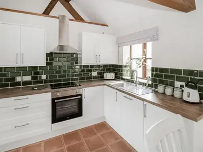 a kitchen with white cabinets and green tiles at Uk46555 - Ragleth in Church Stretton