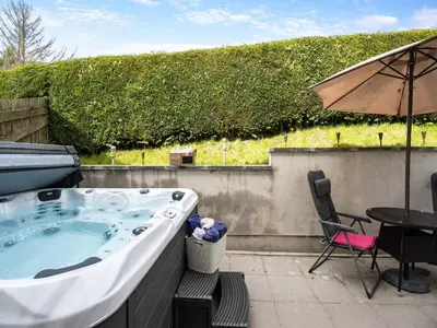 a hot tub on a patio with a table and a chair at Derwen Haidd in Llanafan