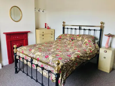a bedroom with a bed with a floral bedspread at Llangollen Townhouse 4 bedroom in Llangollen