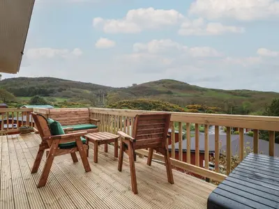 a balcony with two chairs and a view of the water at Y Goedlan in Tywyn