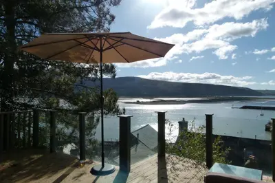 an umbrella on a deck with a view of the water at 2-Bedroom cottage in Barmouth old town with sea views in Barmouth