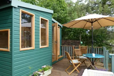 a green tiny house with a table and an umbrella at 2-Bedroom cottage in Barmouth old town with sea views in Barmouth