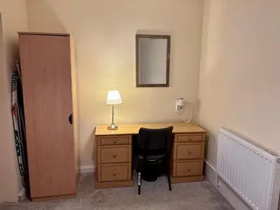 a bedroom with a desk with a lamp and a chair at Marine Apartment in Aberystwyth