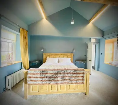 a bedroom with a large bed with blue walls at Apartment at Llanerchydol Hall in Welshpool
