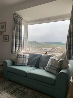 a blue couch in a living room with a large window at Mountain views in the heart of Brecon Town in Brecon